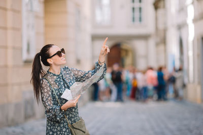 Young woman wearing sunglasses while standing in city