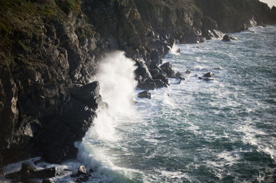 High angle view of waves splashing rocks at sea