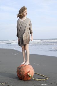 Rear view of woman standing at beach against sky