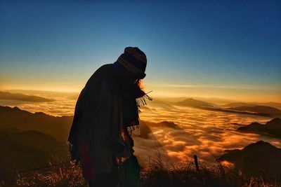 Man standing on mountain against sky during sunset