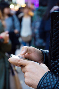 Close-up of hand holding mobile phone in city