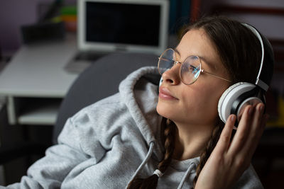 A young brunette girl gazes into the distance listening to music on wireless headphones.