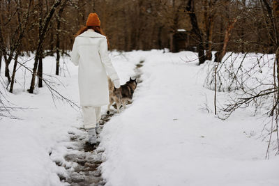 Rear view of woman standing on snow covered field