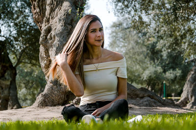 Young woman sitting on tree against plants