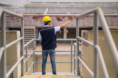 Rear view of man working on railing