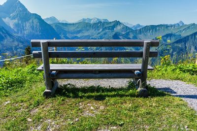 Empty bench in park against mountains