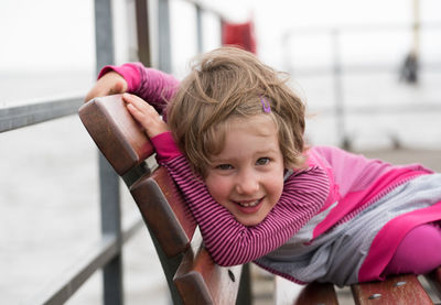 Portrait of cute playful girl sitting on bench