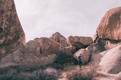 Woman standing on rock formation against sky