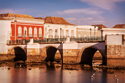 Arch bridge over river in city against sky