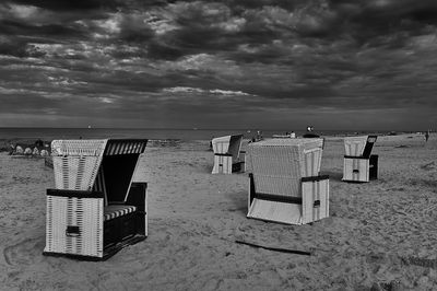 Hooded chairs on beach against sky