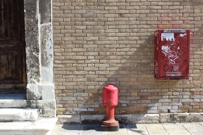 Red fire hydrant against brick wall