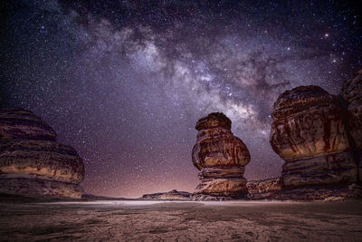 Rock formation in sea against sky at night