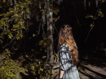 Woman standing by plants in forest