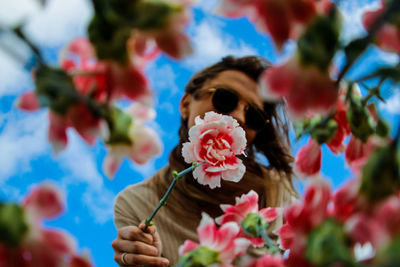 Close-up of woman holding red flowering plant