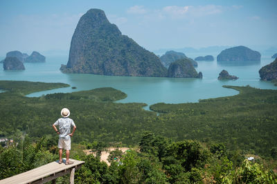 Rear view of man standing on mountain against sky