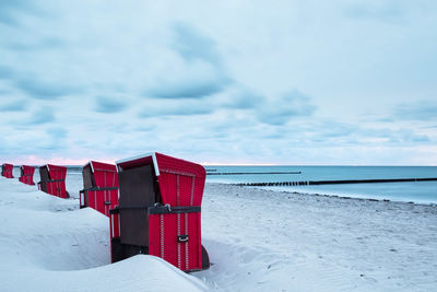 Lifeguard hut on beach against sky during winter