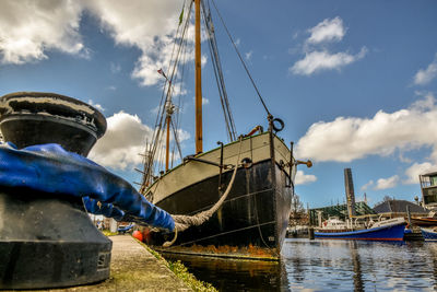 Fishing boats moored at harbor against sky