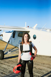 Young female skydiver with backpack in an airfield with plane