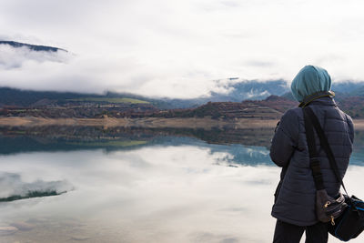 Unrecognizable teenage takes picture about the reflection of the mountain over the lake