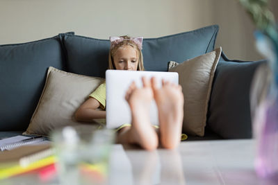 Midsection of woman using mobile phone while sitting on sofa at home