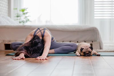 Full length of woman exercising at home with dog