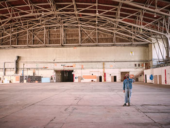 Man dressed in denim throws can of paint in air in an empty building