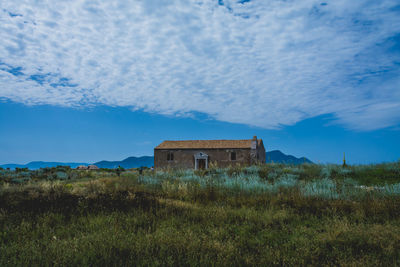 Abandoned house on field against sky