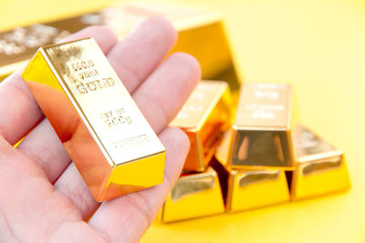 Close-up of hand holding gold ingot at table