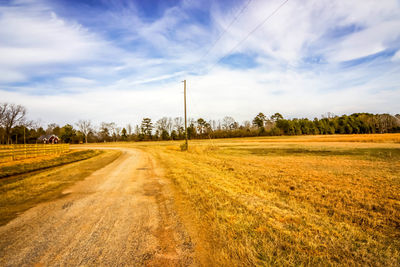 View of field against cloudy sky