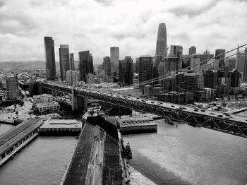 Modern buildings by river against sky in city