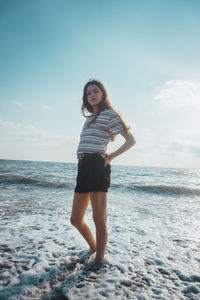 Full length of young woman standing on beach