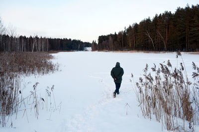 Rear view of person on snow covered pond