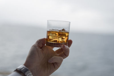 Cropped image of hand holding whiskey glass