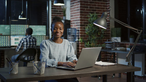 Smiling businesswoman using laptop in office