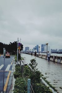 Cars on street by city against sky