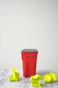 Close-up of red and yellow garbage on floor against white background