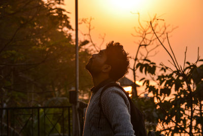 Rear view of woman standing against sunset sky