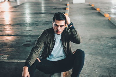 Full length portrait of young man sitting in city