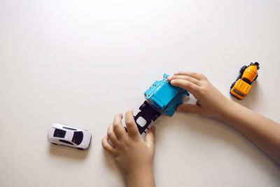 Cropped hand of person holding toy car against white background