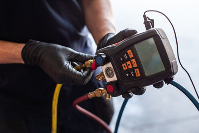 Crop man with modern voltage tester selecting cables while fixing machine in workshop