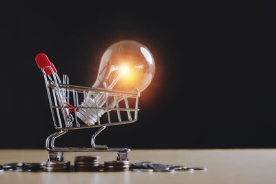 Close-up of illuminated light bulb on table against black background