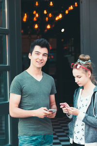 Smiling teenage friends using mobile phone in city