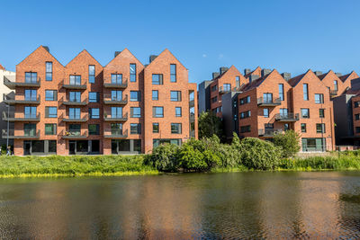 Residential buildings by river against clear sky