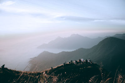 Tourists on mountain against sky