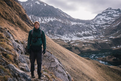 Man standing on snowcapped mountain against sky