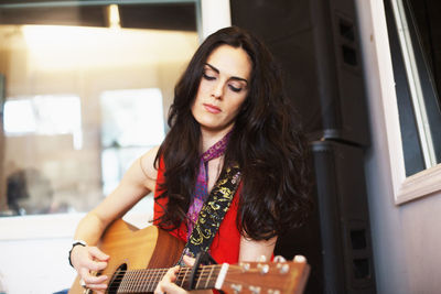 Young woman playing acoustic guitar at a recording studio