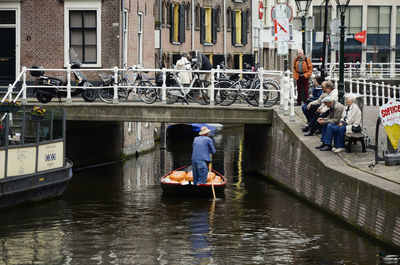 People on boat in canal along buildings