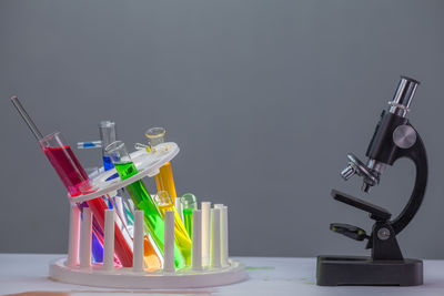 Close-up of multi colored chemicals in laboratory glassware by microscope on table against gray background