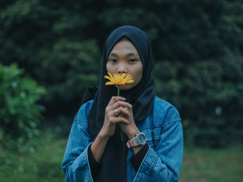 Portrait of beautiful young woman holding red flower