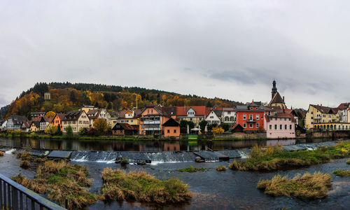 Houses by river against sky